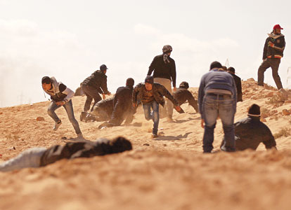 Libyan rebels duck for cover as they come under tank fire from Moammar Gadhafi's forces. AFP photo